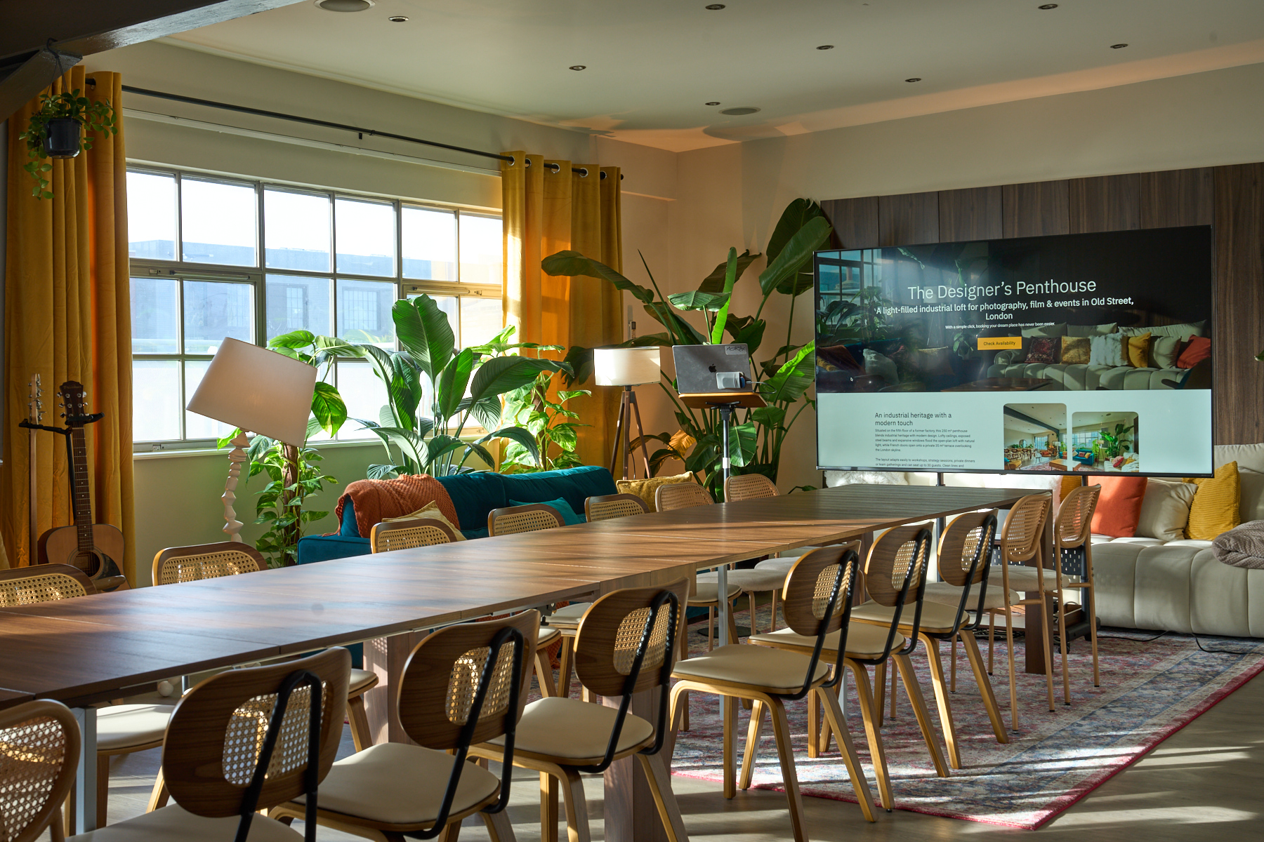 Meeting setup with long table, TV, and reading desk in natural daylight at The Designer's Penthouse