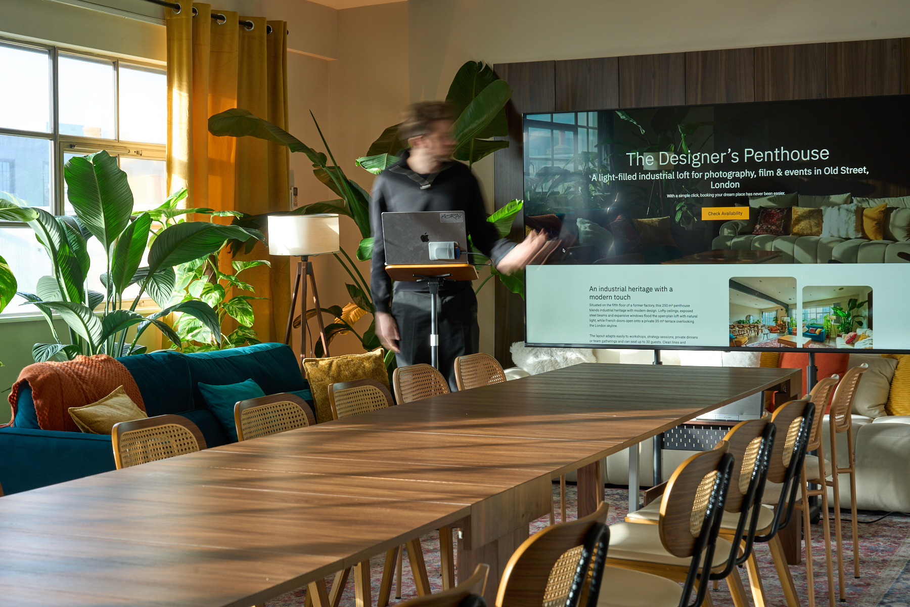 Meeting space configured with long table, display screen, and natural daylight in the penthouse