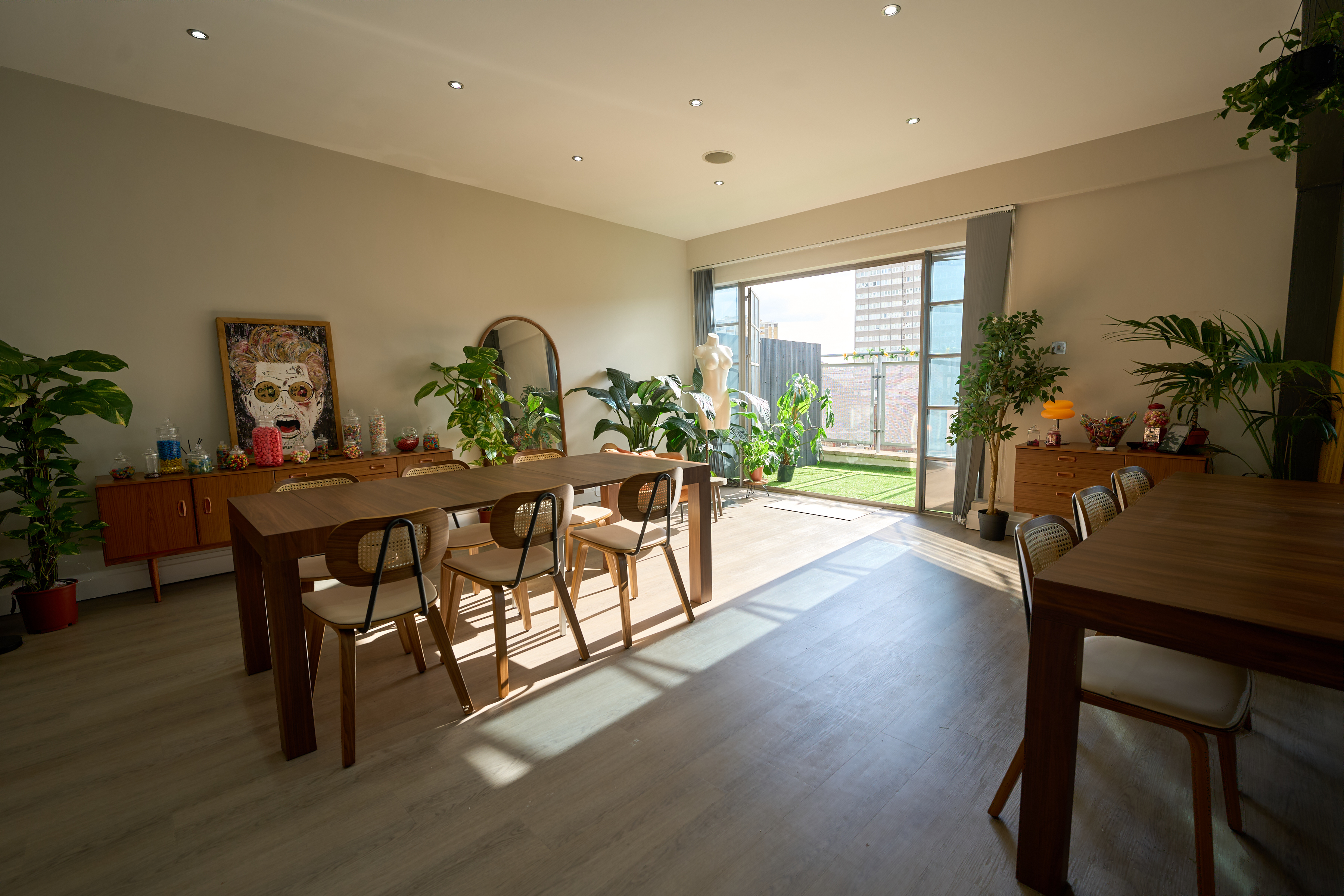 Dining room with artwork, walnut sideboards, and open doors to the rooftop terrace at The Designer's Penthouse, Old Street London