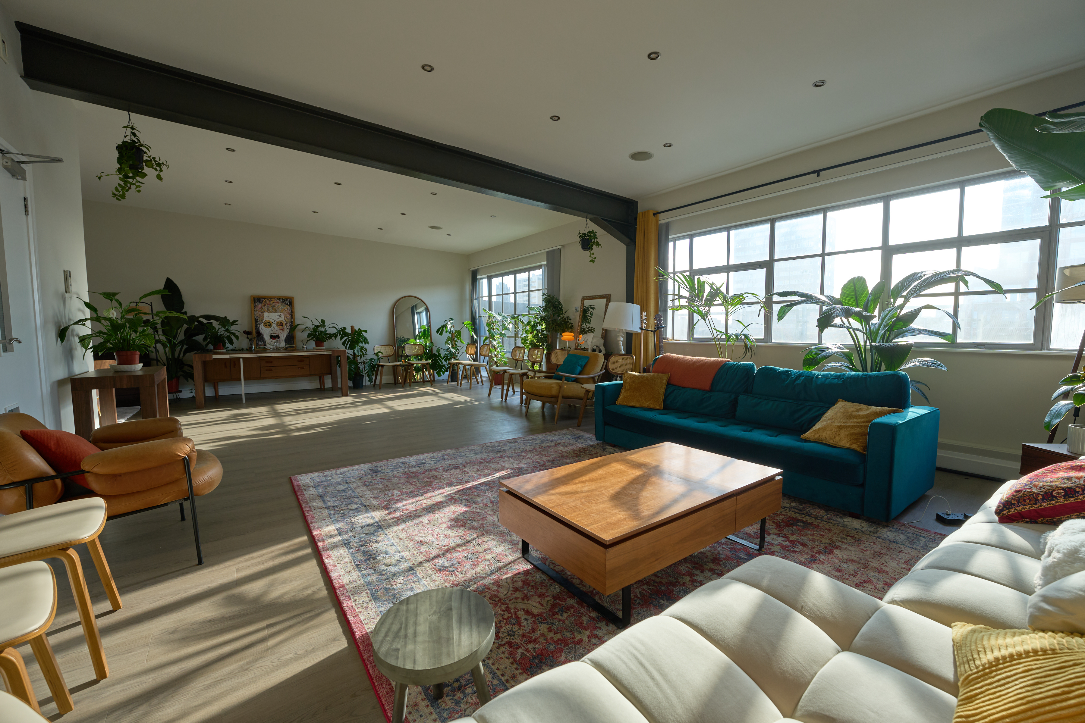 Spacious open-plan living room with teal sofa and mid-century furniture at The Designer's Penthouse
