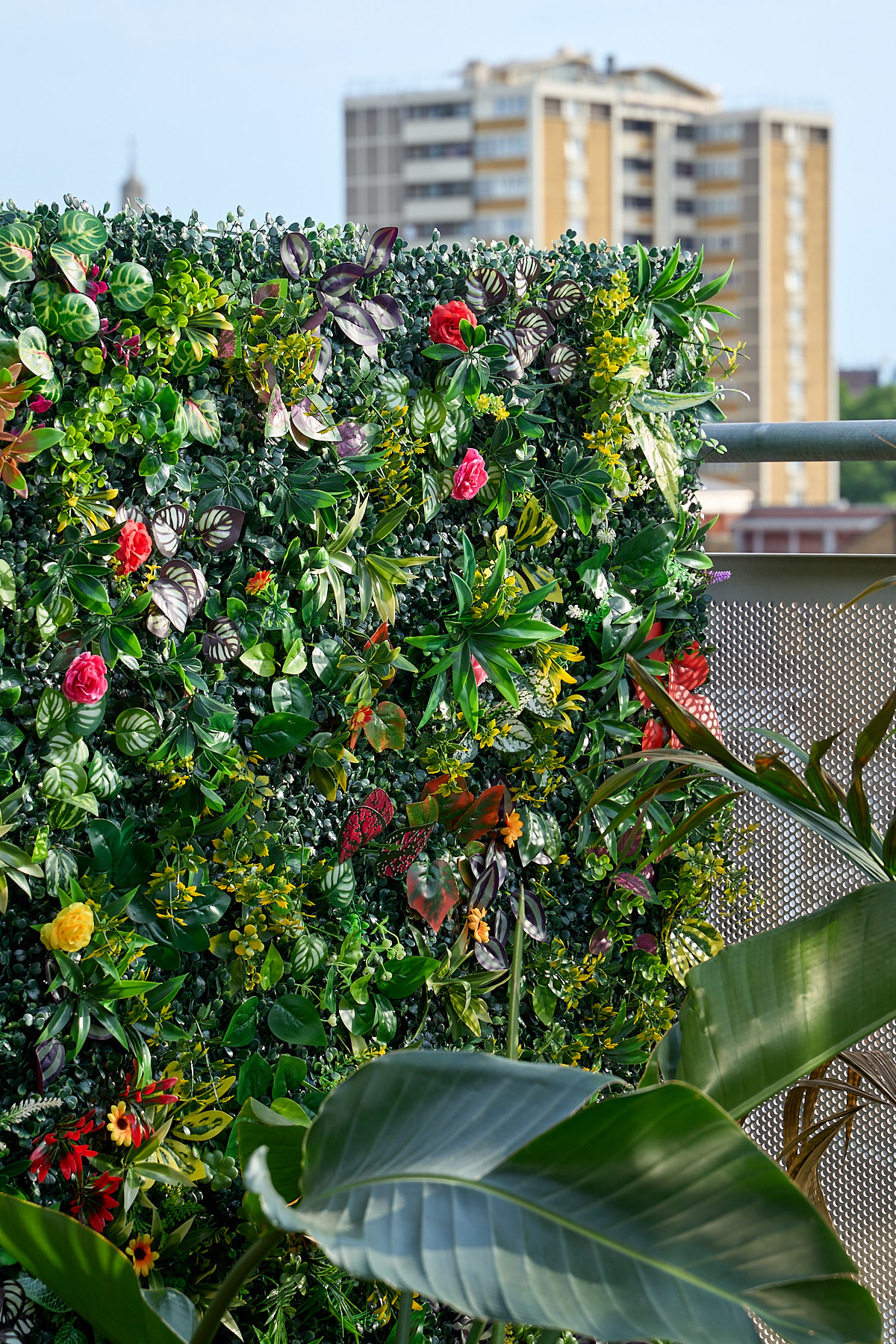 Lush artificial flower wall in full summer bloom against the London skyline on the rooftop terrace at The Designer's Penthouse, Old Street