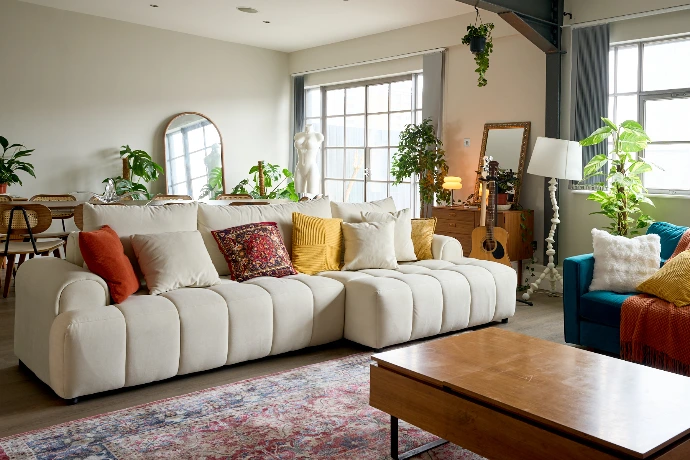 Elegant living room in a London penthouse with sofa seating, plants, and warm natural light.
